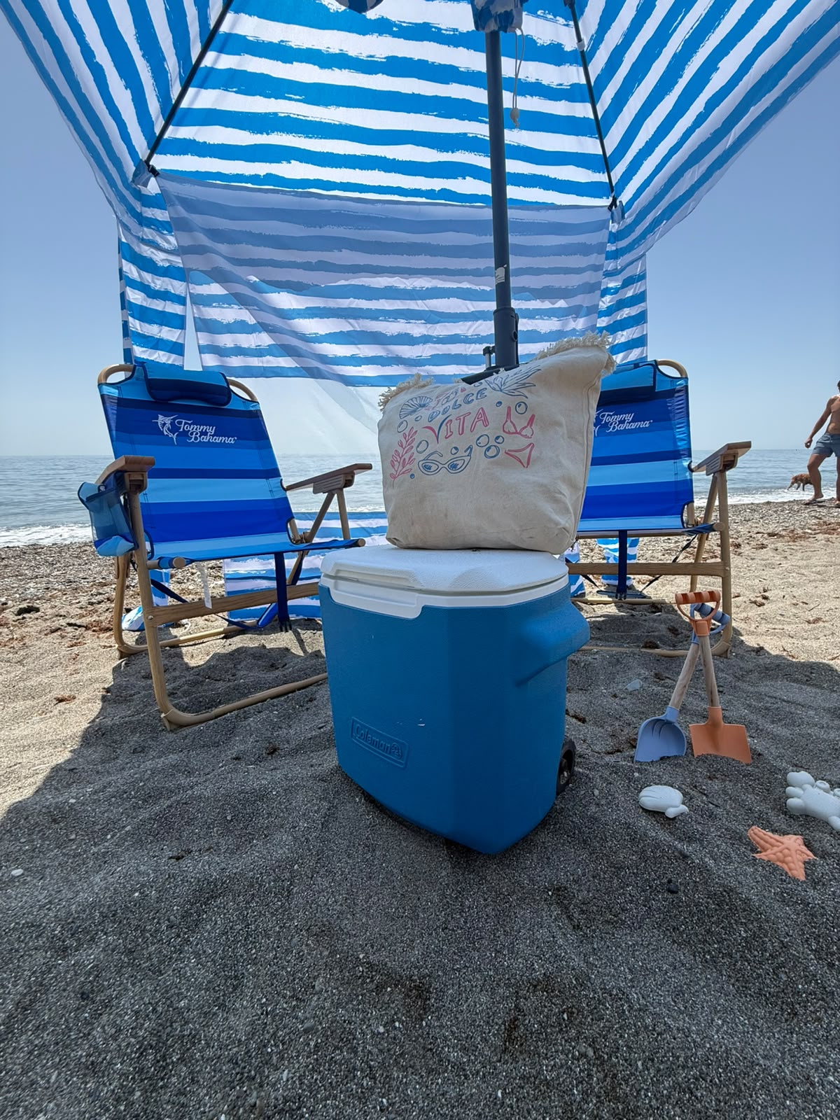 Sillas de playa, sombrilla y nevera en la arena